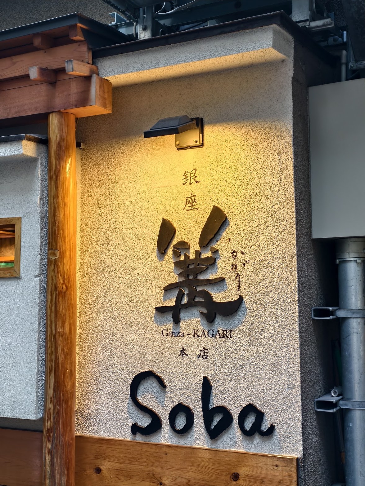 スポットライトに照らされた漆喰壁に「銀座 篝 Ginza-KAGARI 本店 Soba」の文字と大きな篝の筆文字看板